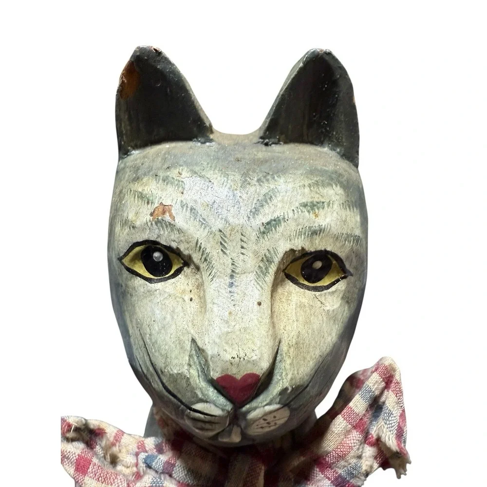 hand-carved wooden cat figurine with a painted finish and a plaid cloth scarf.